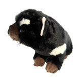 Plush toy resembling a dog with black, brown, and white fur on a white background