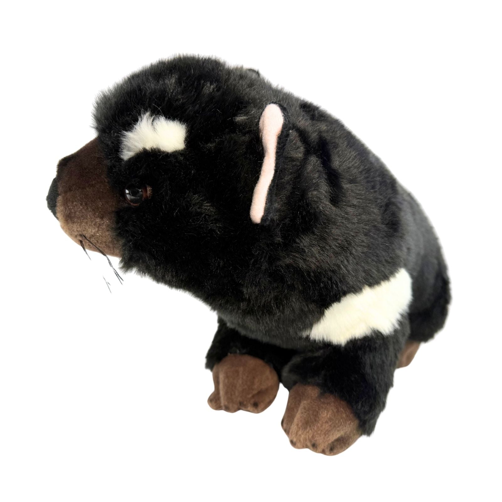 Plush toy resembling a dog with black, brown, and white fur on a white background