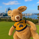 Plush kangaroo toy wearing an 'Australia' shirt with a map of Australia on it, set against a cityscape with a body of water.