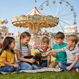 Children sitting on grass at fairground playing with Trixie Burmese kitten plush toy near carousel