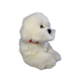 a realistic fluffy white plush dog toy in a lying position