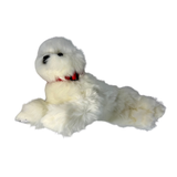 a realistic fluffy white plush dog toy in a lying position