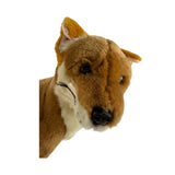A brown realistic soft plush toy black and tan dingo in a sitting position