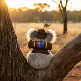 Sitting Jack koala plush with swag and hat on a tree