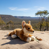 Plush toy dog on a rock with a scenic landscape in the background