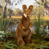 Plush Miles toy in a natural setting with plants and water.