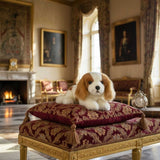 Phoebe Cavalier King Charles plush on ornate cushions in palace.