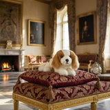 Phoebe Cavalier King Charles plush on ornate cushions in palace.