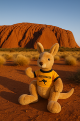 Plush kangaroo toy wearing an 'Australia' shirt in front of Uluru.