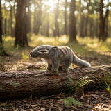 Small creature standing on a log in a forest with sunlight filtering through the trees.