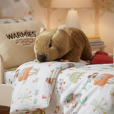 Wallis wombat plush toy with satin pocket resting on bed