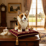 Windsor Welsh Corgi plush toy sitting on ornate red velvet cushion with gold crown in elegant room