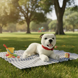 Winter Staffy plush toy lying on picnic blanket with toys and apple in sunny park